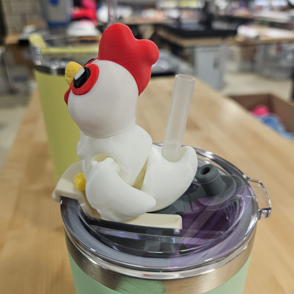 Green tumbler with a chicken-shaped straw lid on a wooden surface
