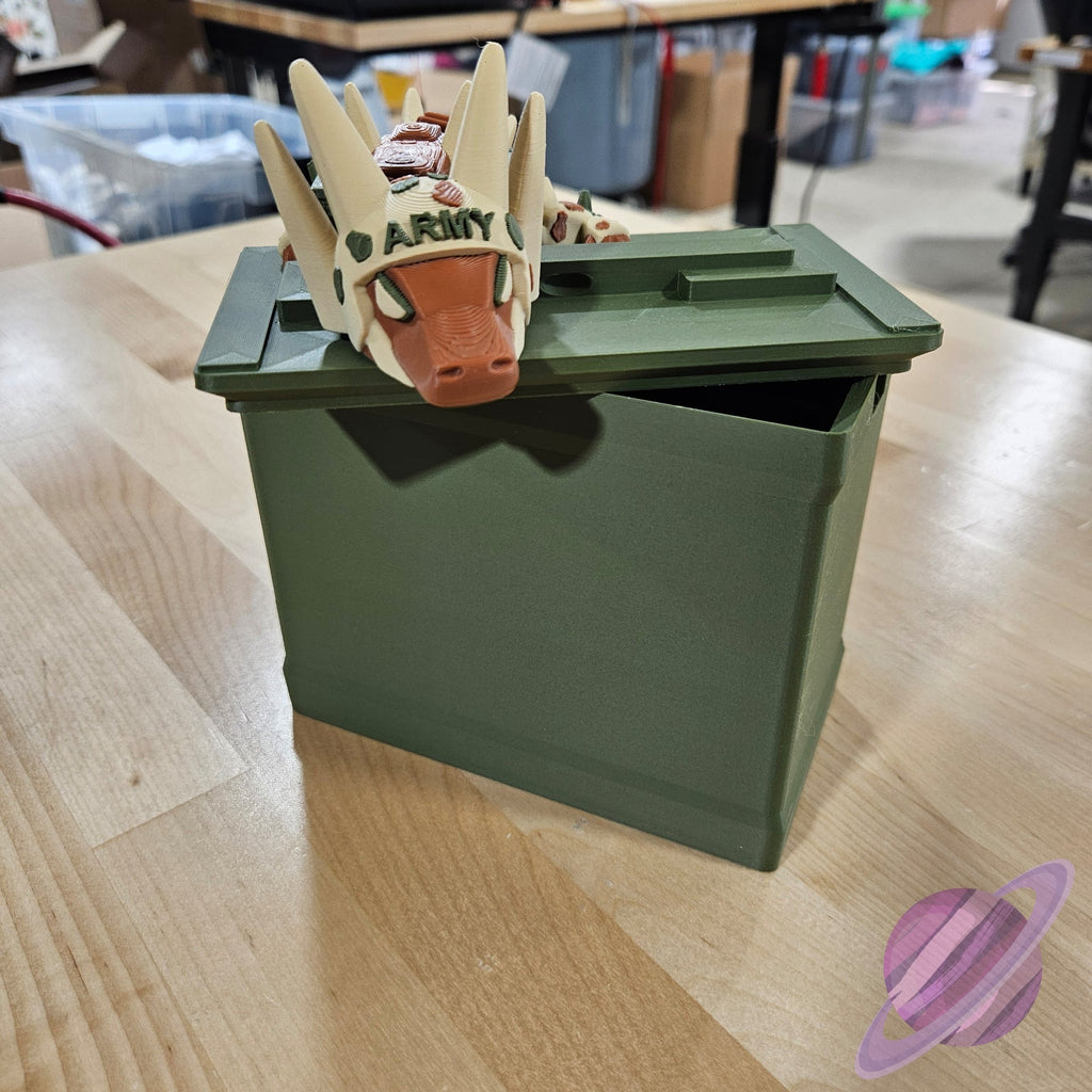Toy dragon head on top of a green ammunition box on a wooden surface