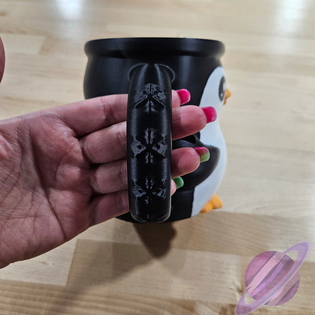 Hand holding a black mug handle with floral patterns on a wooden surface