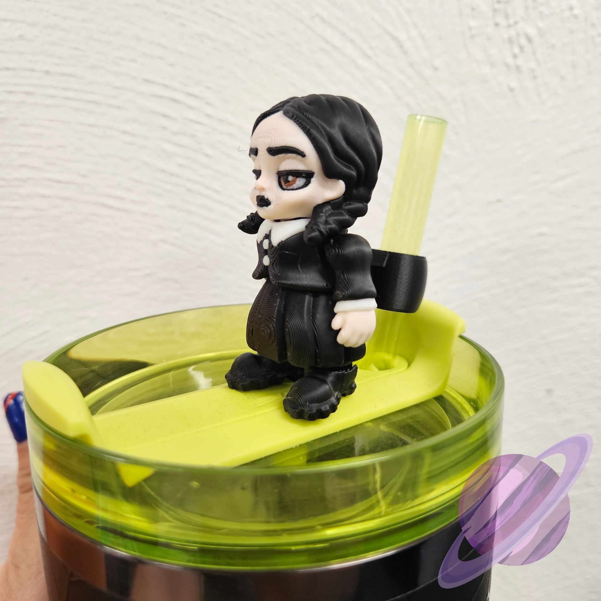 Figurine of a character with long hair and a black outfit on top of a green container.