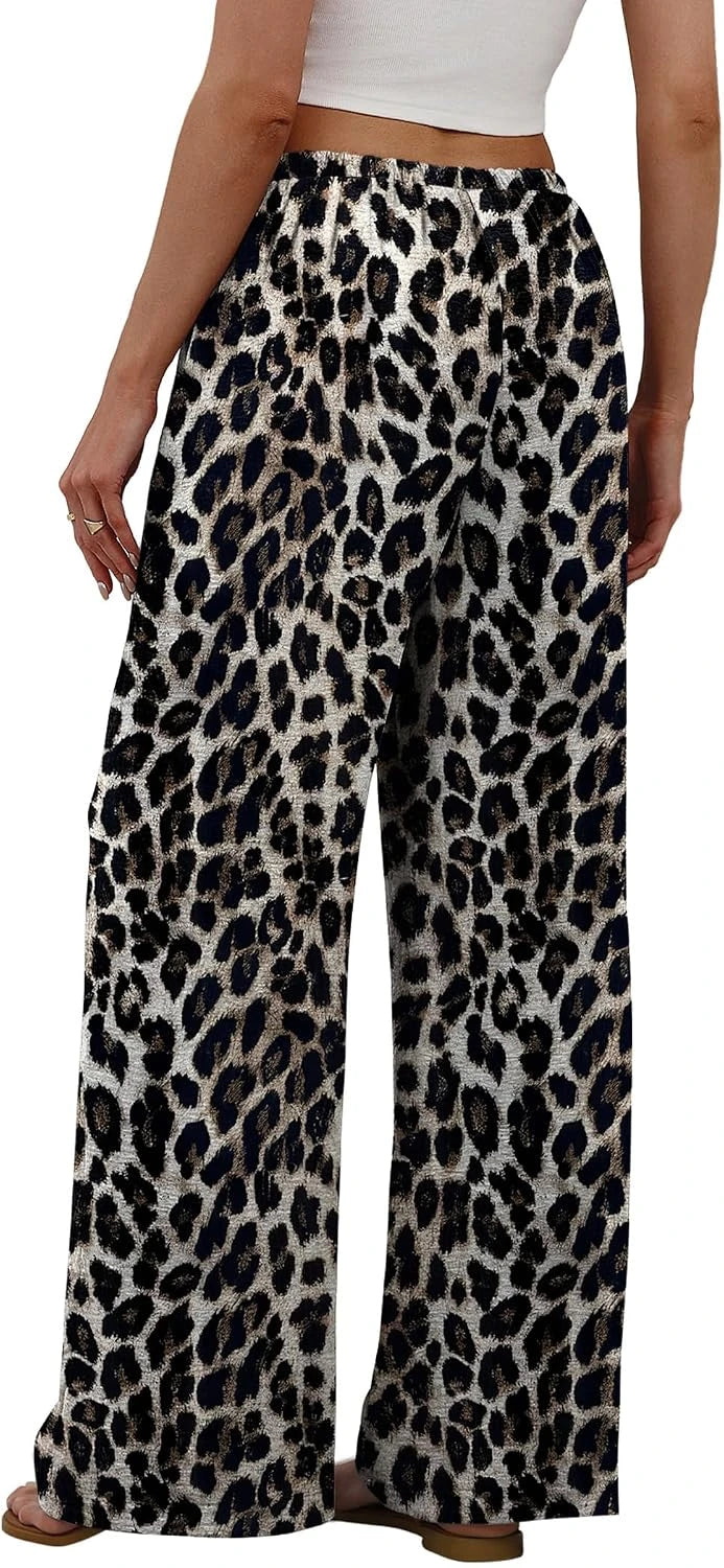 Wide-leg pants with an all-over leopard print pattern in black, brown, and beige, shown on a model from the waist down against a plain white background.