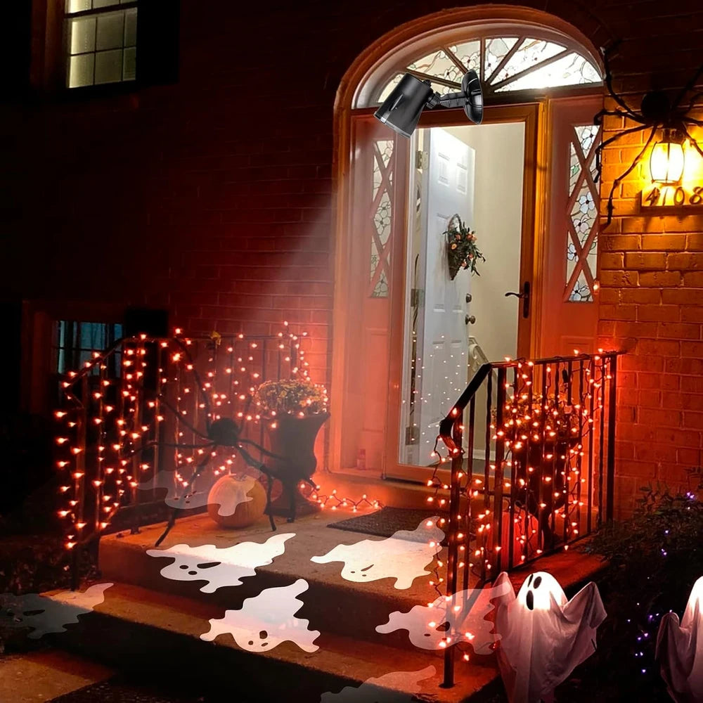 Halloween front porch decorated with warm white string lights draped over a brick door, ghost cutouts on the steps, white ghost decorations, a pumpkin, and a spider web light.