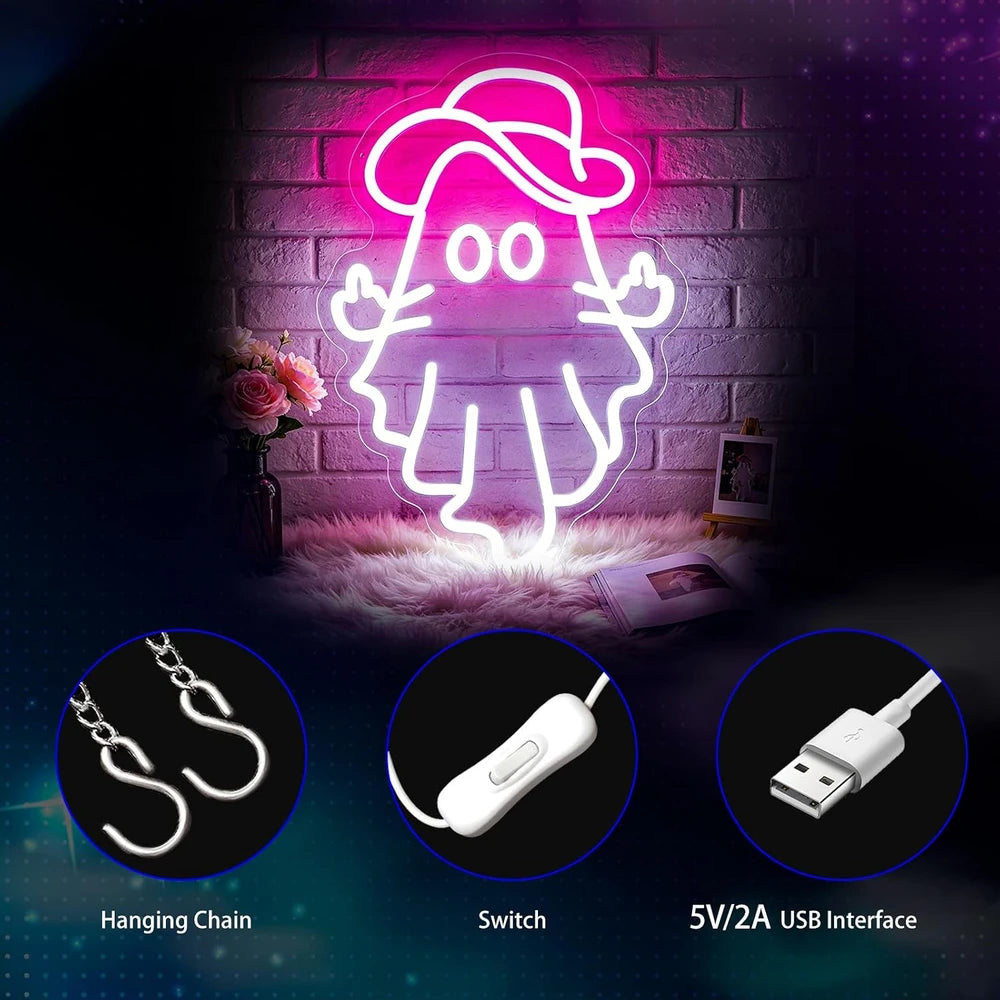 A neon-style ghost-shaped wall sign glowing pink and white, mounted against a dark brick wall with decorative props below. Three circular inset callouts show included accessories: a hanging chain, a white inline switch, and a 5V/2A USB cable interface.