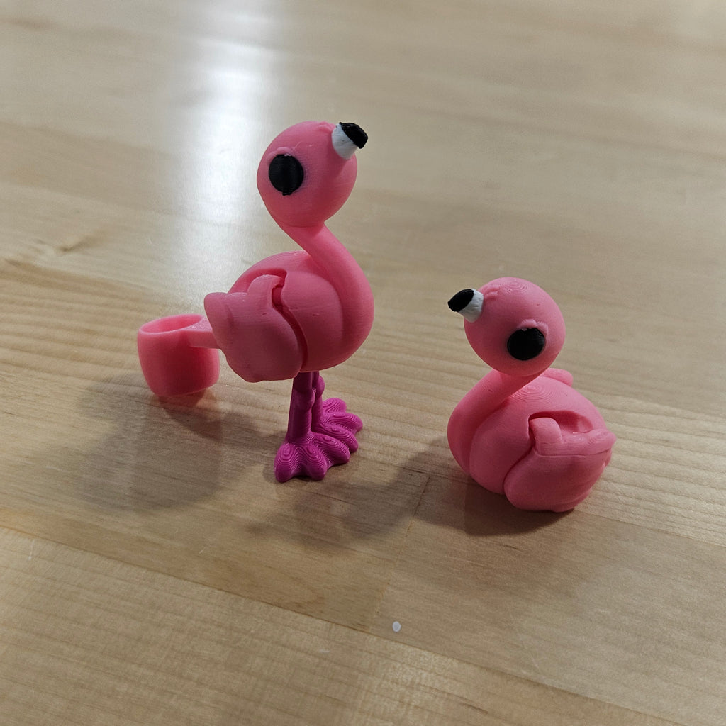 Two pink flamingo-shaped hair ties on a wooden surface