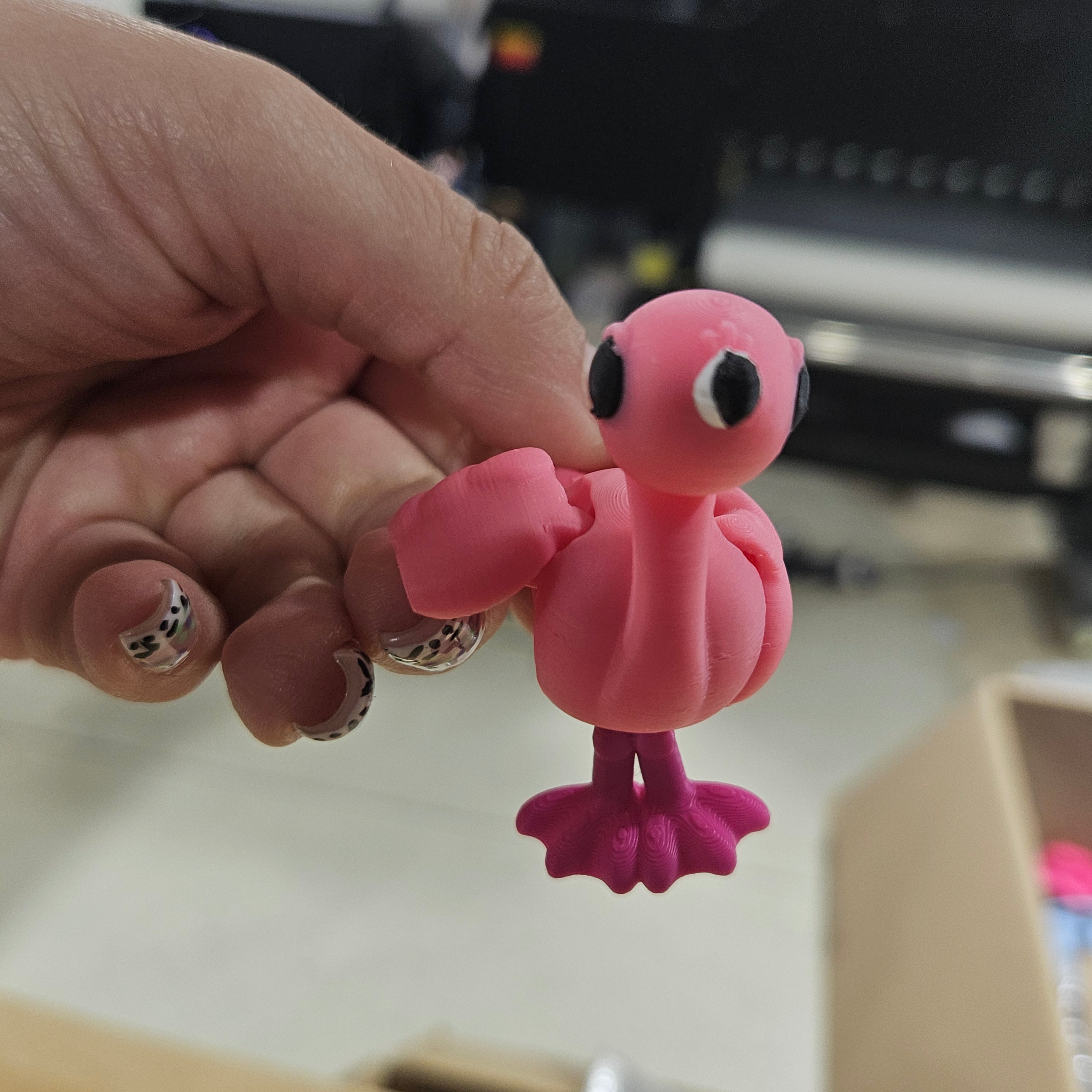 Pink toy figure held in a hand with a blurred background