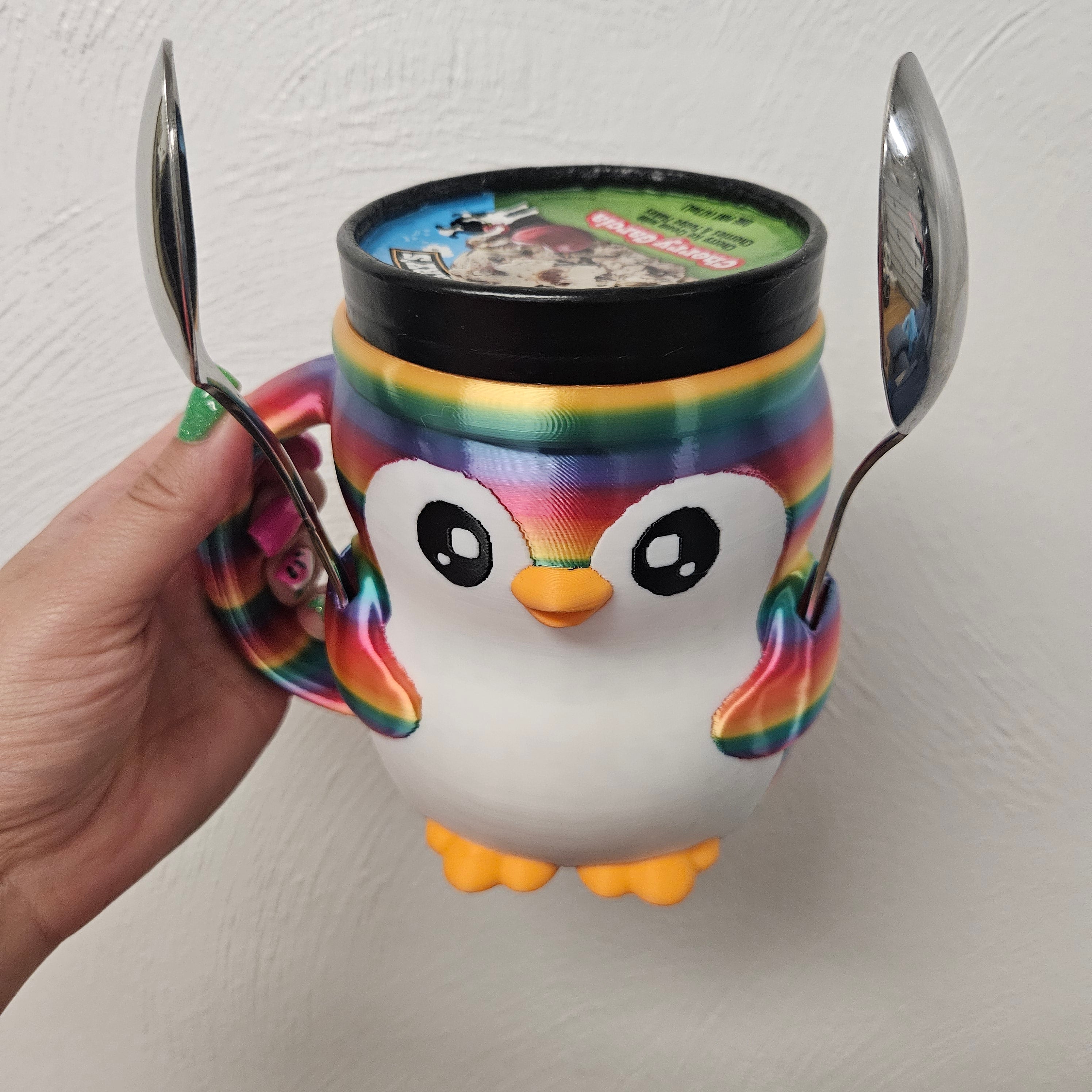 Colorful penguin mug with a lid and two spoons on a white background