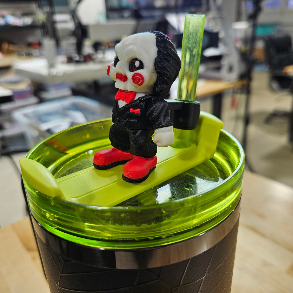 Green and black container with a small figurine on top in an indoor setting