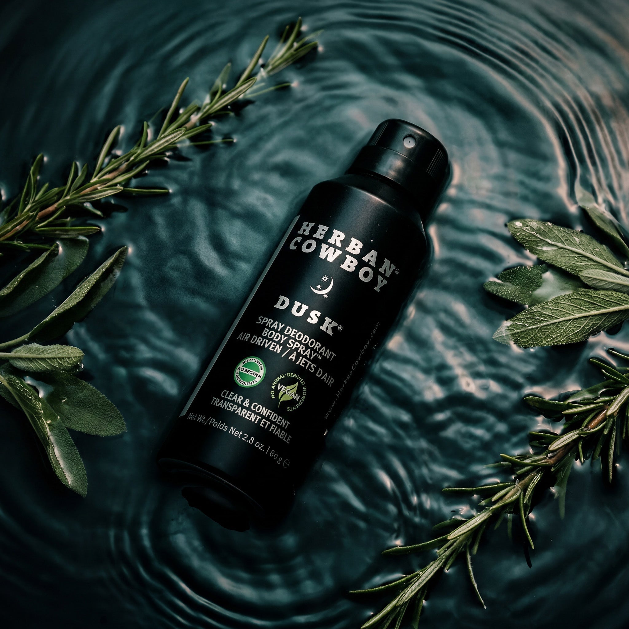 Herbal Cowboy Dusk spray deodorant on water with green leaves