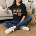 Person wearing a black t-shirt with colorful text in a living room.