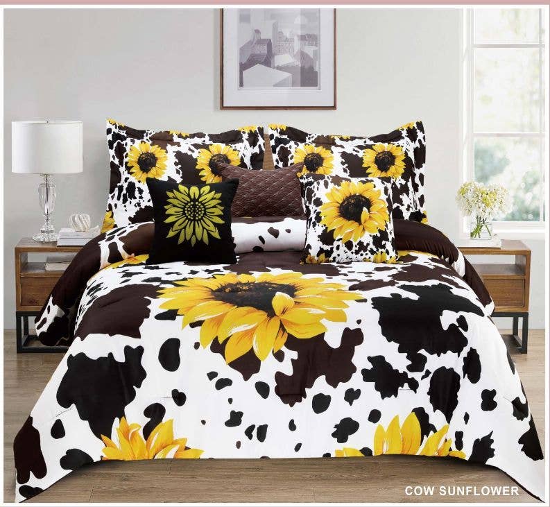 A bed dressed in a cow-print bedding set with large yellow sunflower motifs, including a comforter, matching pillow shams, and a decorative throw pillow, shown in a styled bedroom setting.