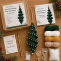 DIY crochet spiral Christmas tree ornament kit laid out on a wooden surface with its box, instructions card, yarn balls, crochet hook, star, beads, cord, and finished ornament.