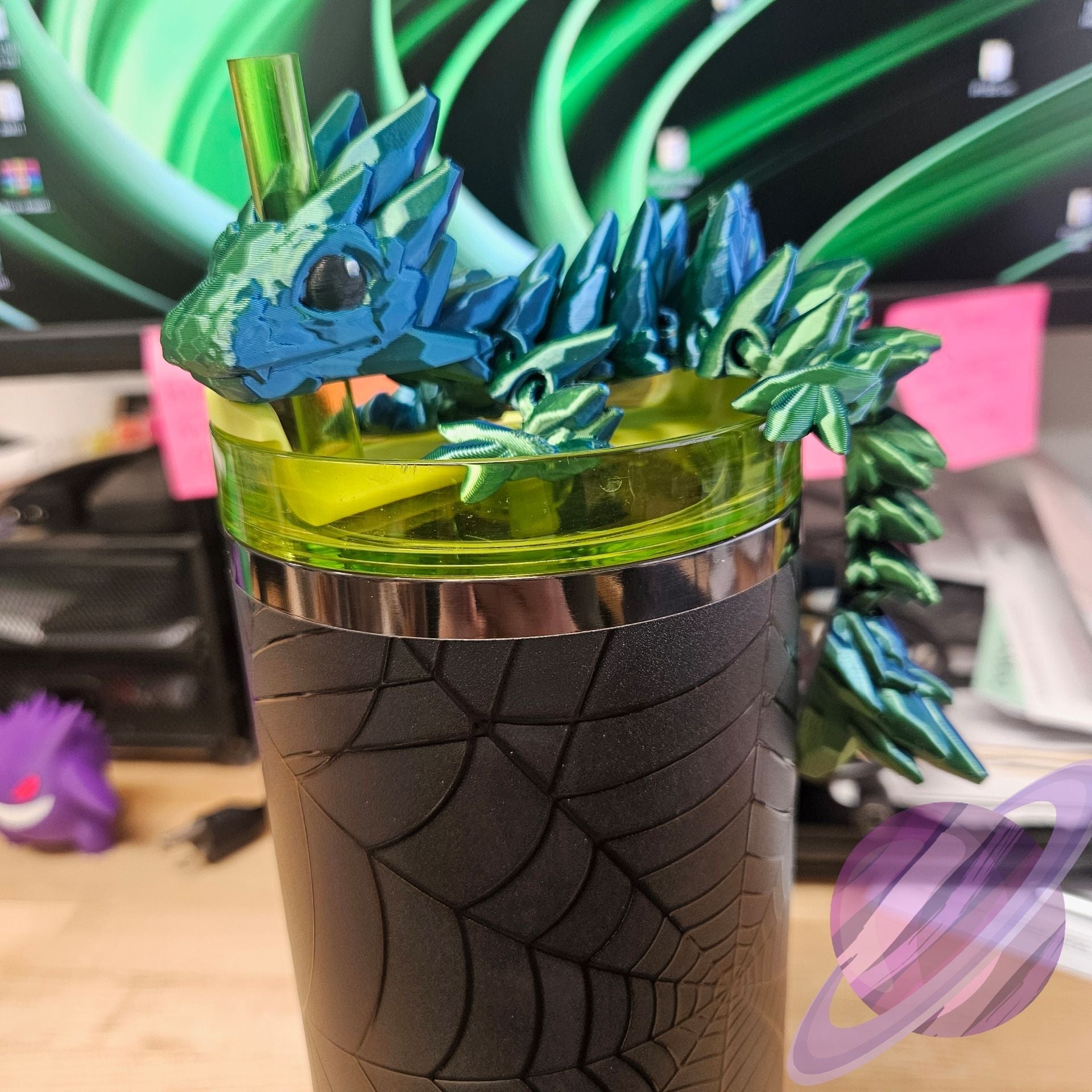 Dragon-themed tumbler with a green lid and black base on a desk.