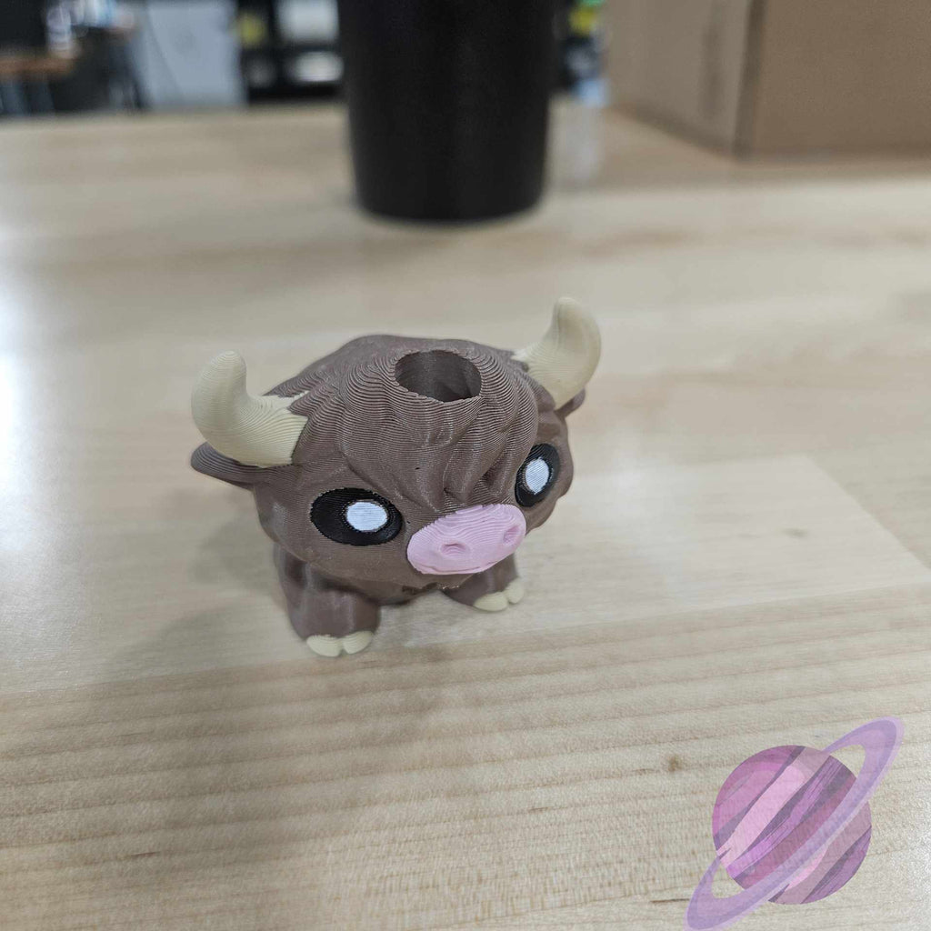 Small figurine of a creature with large eyes and horns on a wooden surface