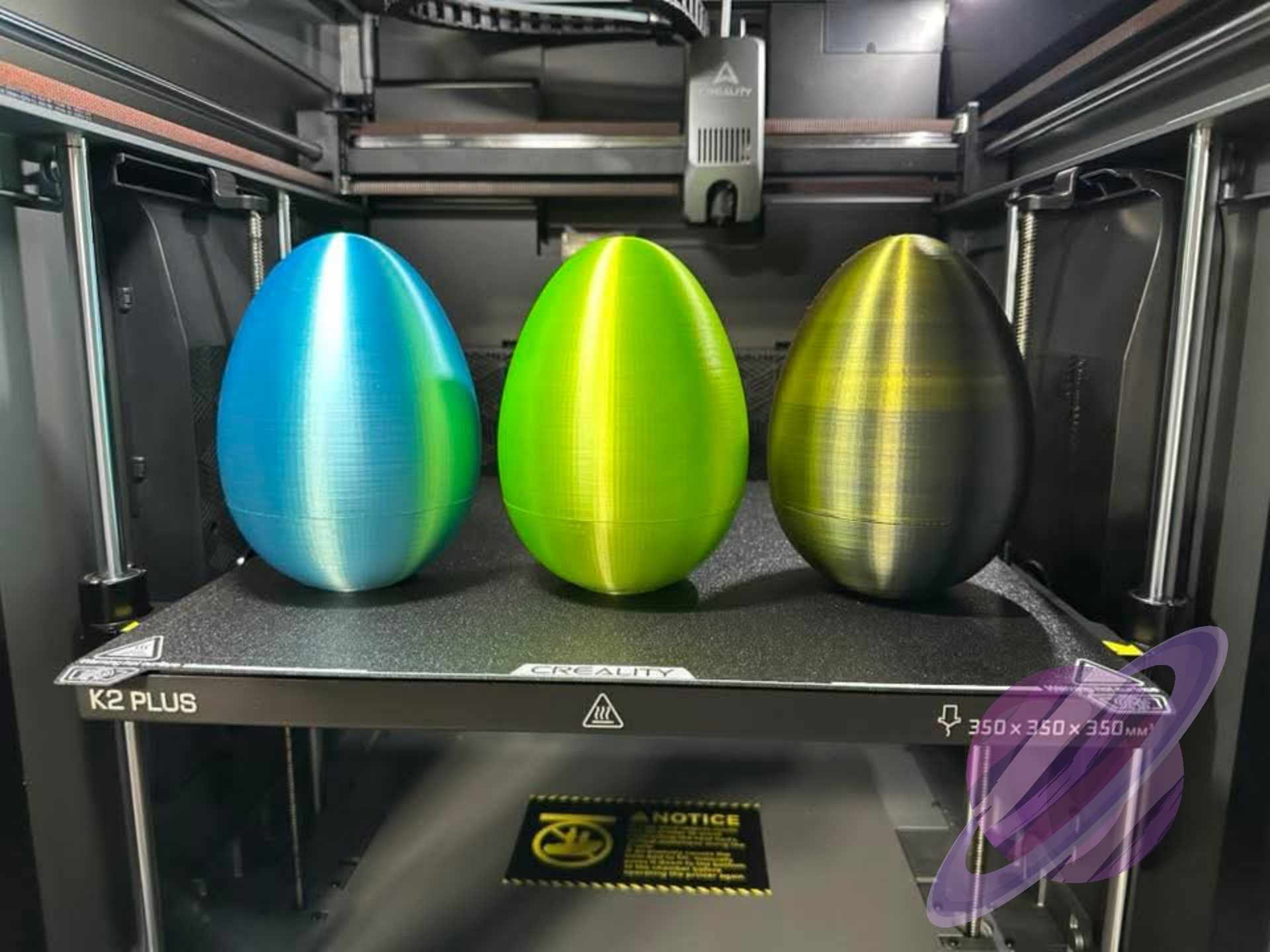 Three colorful 3D-printed objects on a 3D printer bed.
