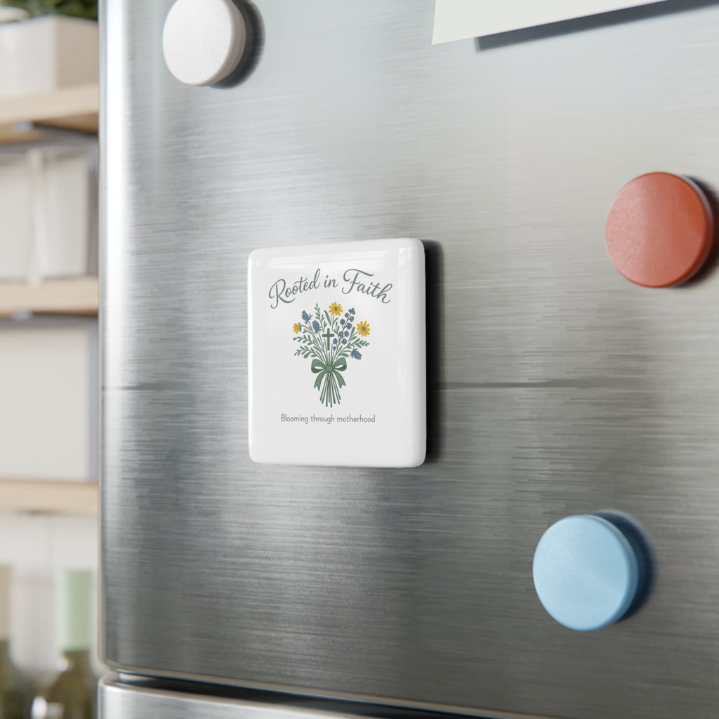 A square white refrigerator magnet with a floral bouquet illustration and the words 'Rested in Faith' and 'Blooming through adversity' is shown attached to a brushed stainless steel fridge door, alongside other colorful magnets.