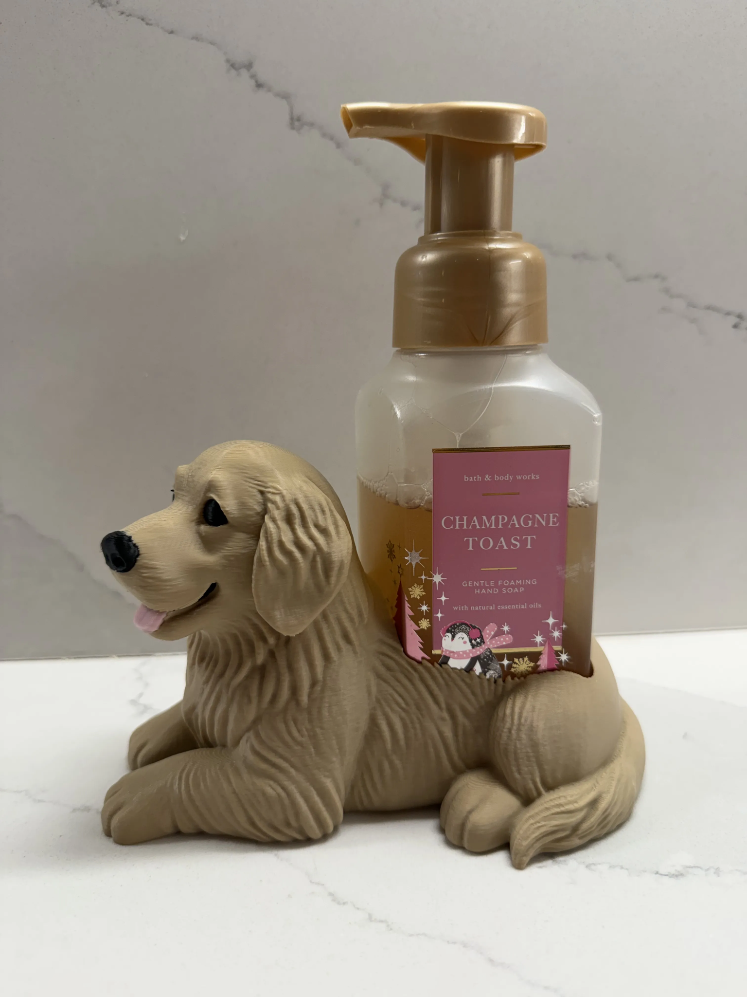A dog-shaped pump dispenser holding a bottle of Bath & Body Works Champagne Toast hand wash, set against a light gray marble background.