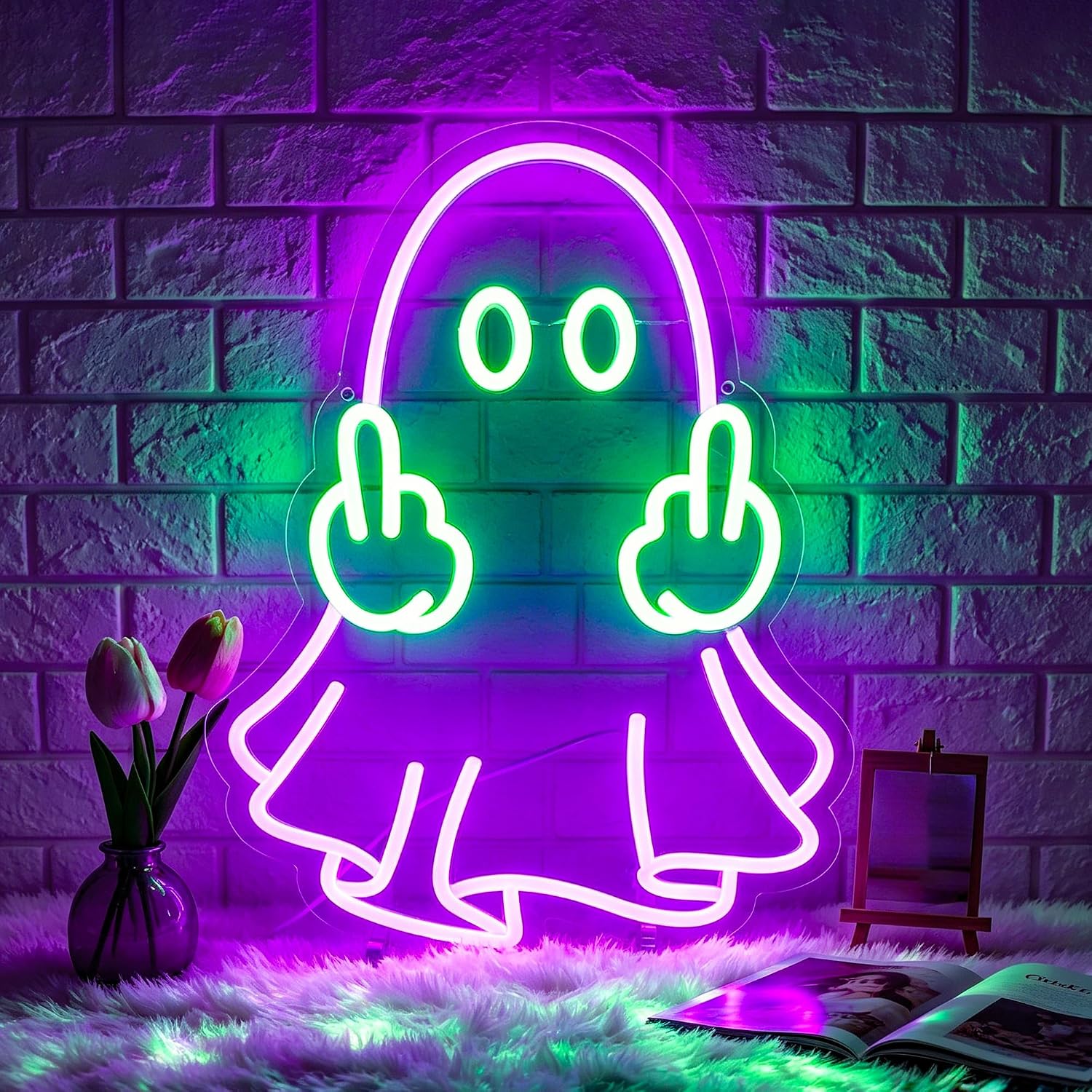 A neon sign shaped like a cartoon ghost with its middle fingers, glowing in purple and green against a brick wall background with decorative props including tulips and an easel.