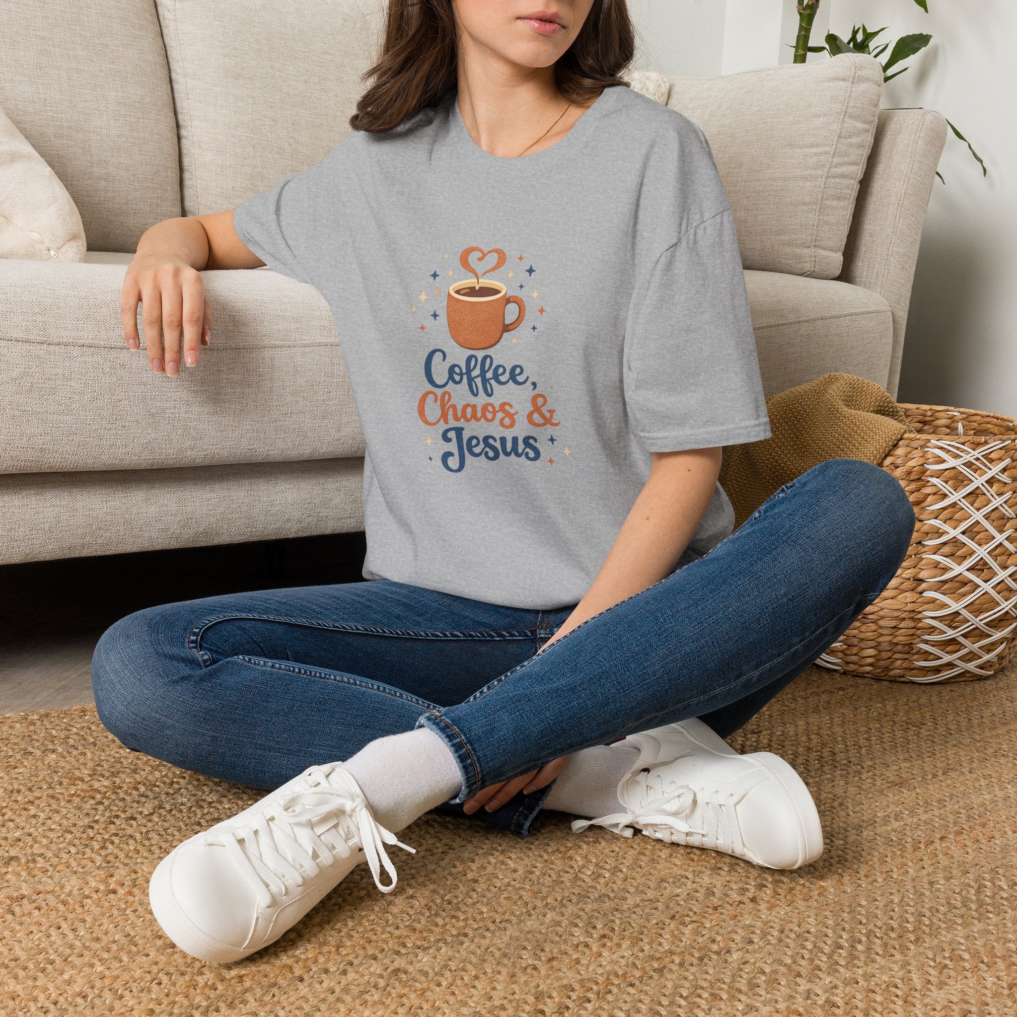 Person wearing a gray t-shirt with outdoor-themed design, sitting on the floor in a living room.