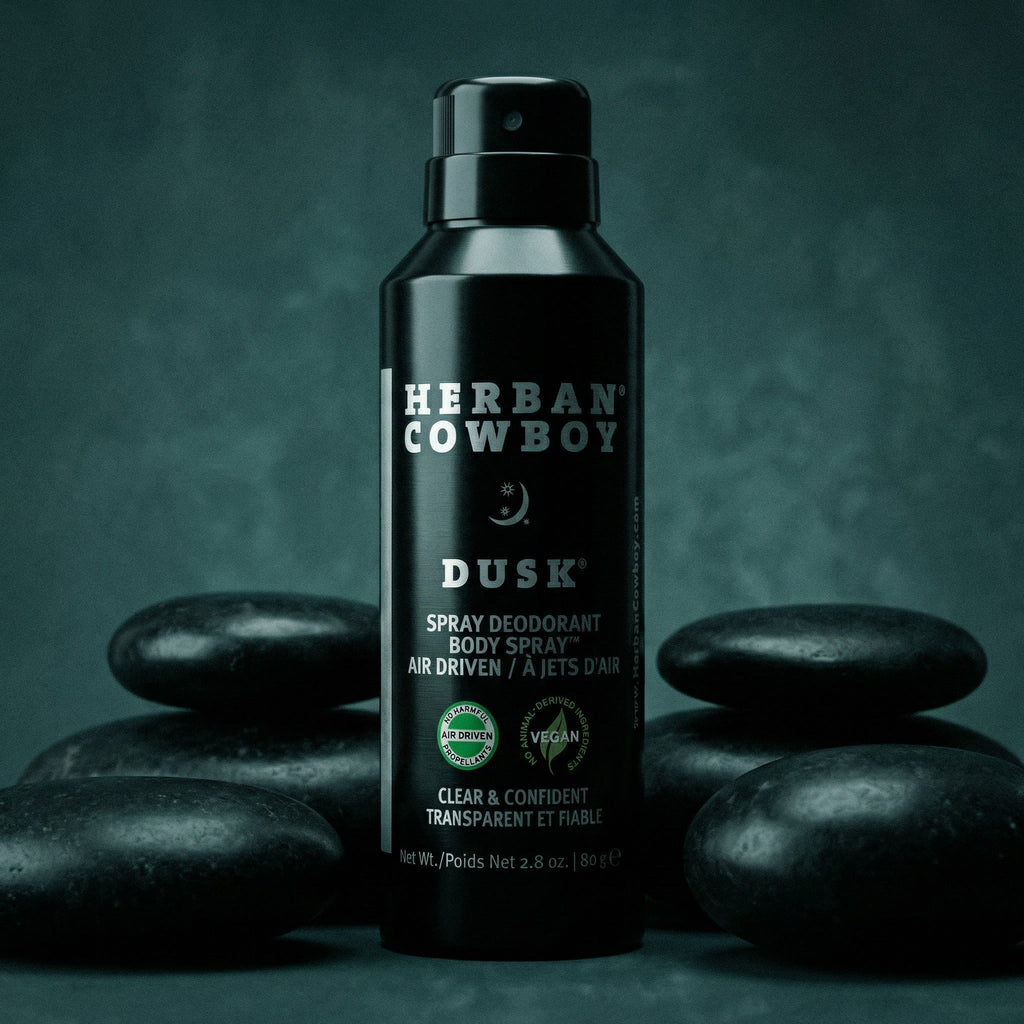 Herban Cowboy Dusk spray deodorant body spray bottle on dark stones with a dark background