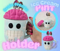 Brain-shaped ice cream pint holder with pink top and black eyes, held by a hand.