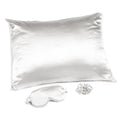 White satin pillow, eye mask, and earplugs on a white background