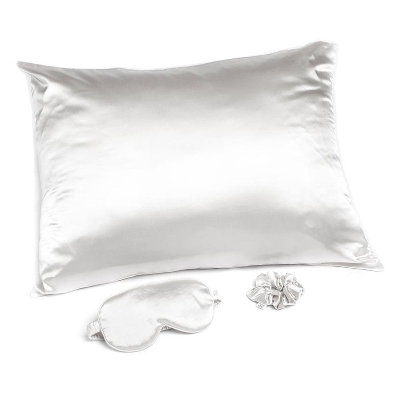 White satin pillow, eye mask, and earplugs on a white background