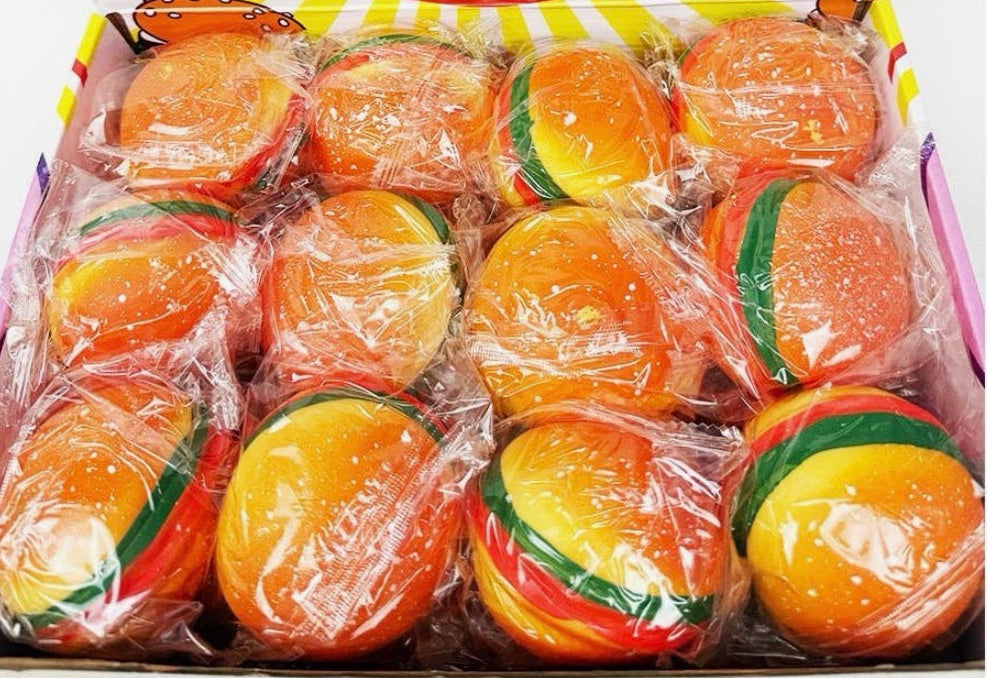 A box of Pinches Hamburger squeezy fun containing  individually wrapped round "burgers" shaped like mini burgers, displayed on a colorful printed cardboard insert.