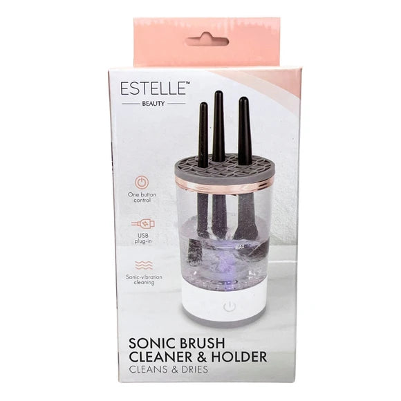 Estelle Beauty Sonic Brush Cleaner & Holder in its retail packaging, featuring a clear cylindrical container with four black bristles, a rose gold metallic collar, and a white base, shown on a white background.