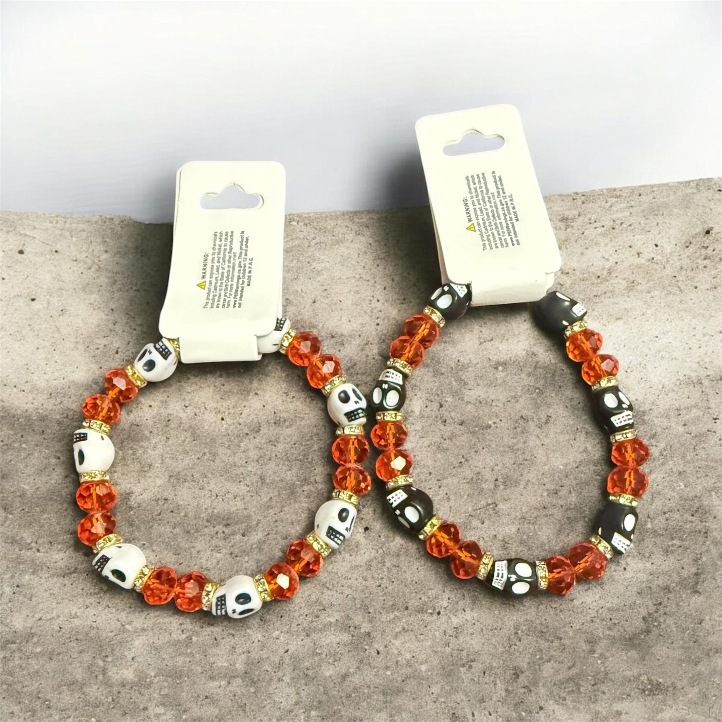 stretch bracelets with bright orange and black beads and white and black skulls