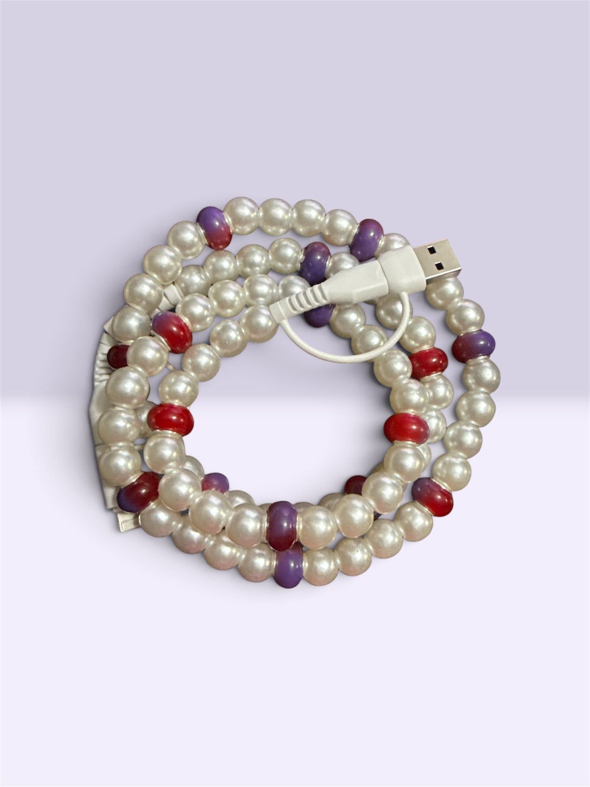 A coiled multi-strand pearl cable with white faux pearls and small accent beads in red, purple, and dark brown, featuring a white USB connector.
