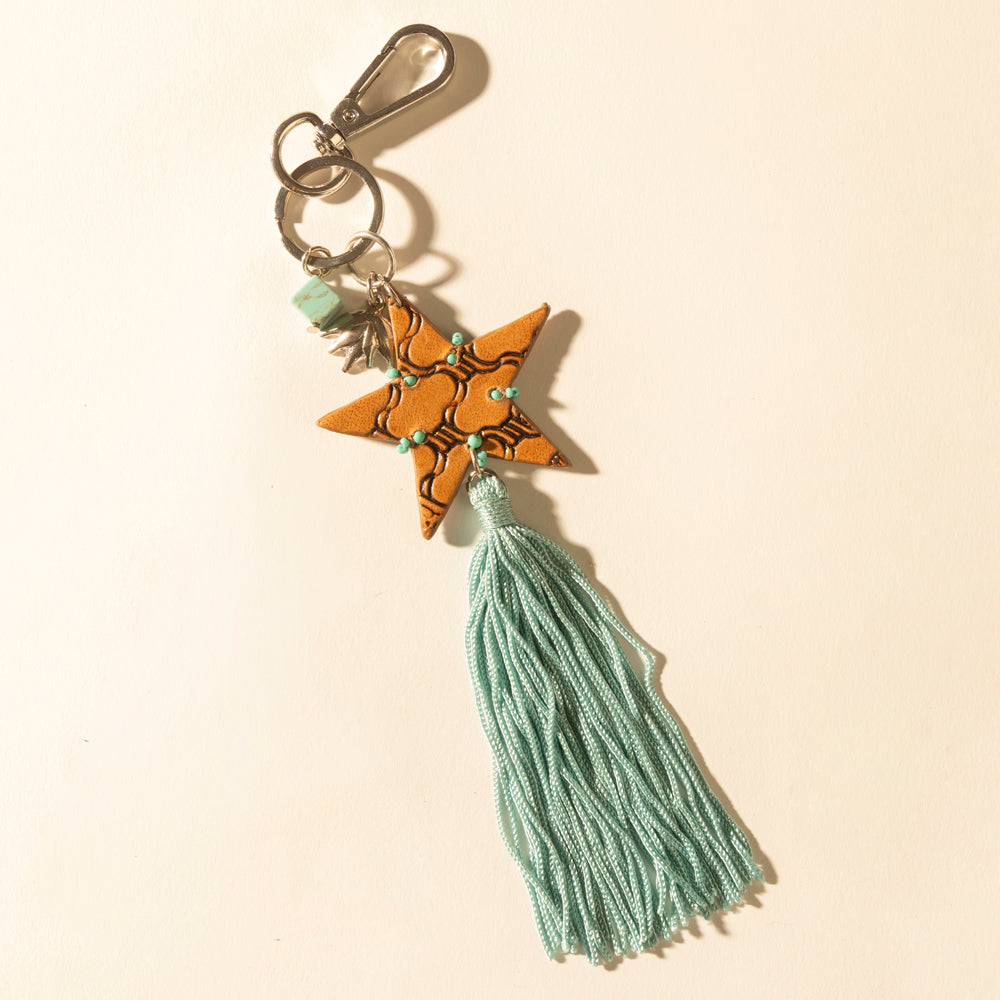 Star-shaped keychain with tassel on a beige background