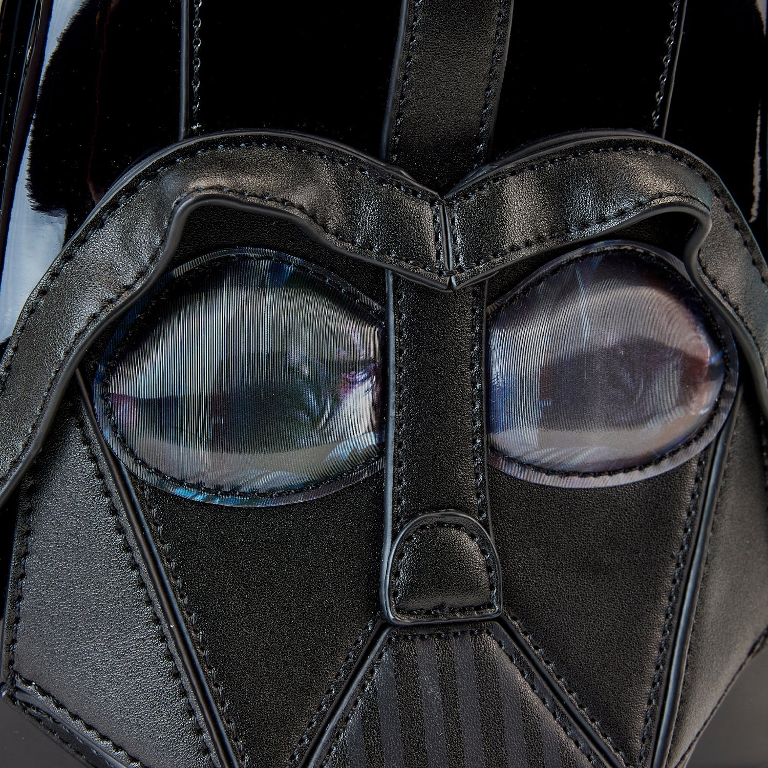 Close-up of a dark mask with detailed design and reflective surface.