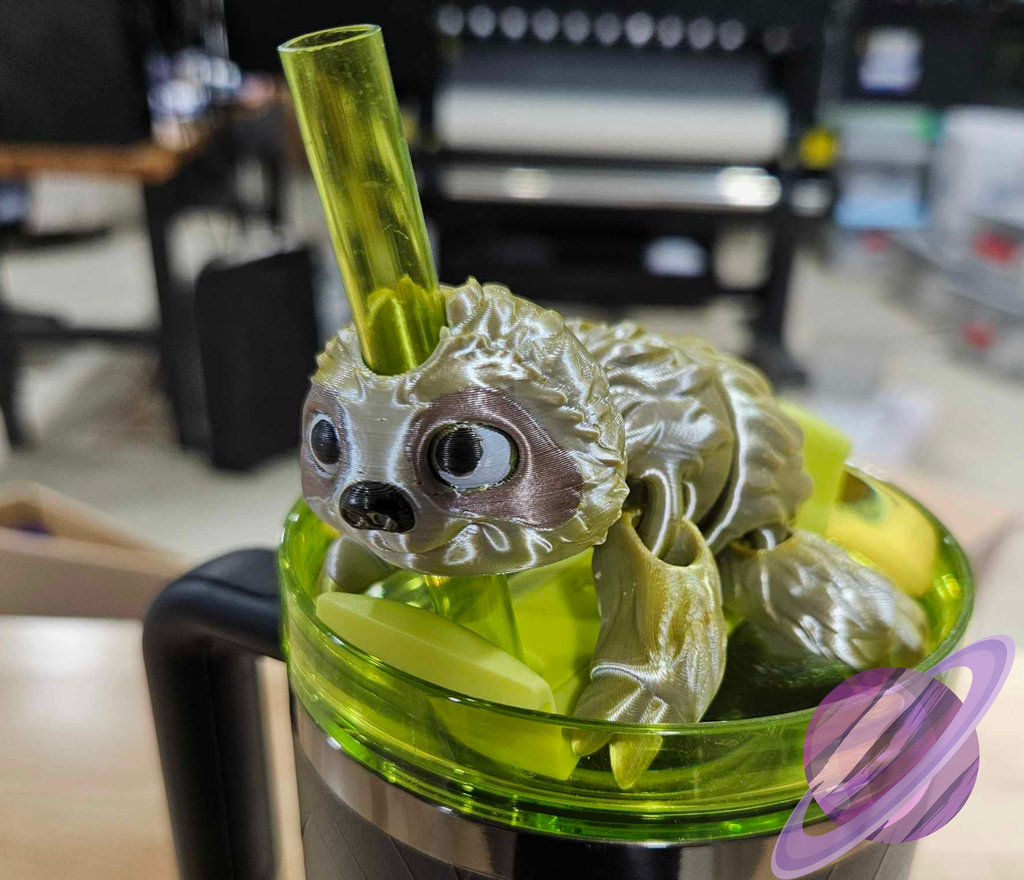 Green sloth-shaped drink container with a straw on a blurred indoor background