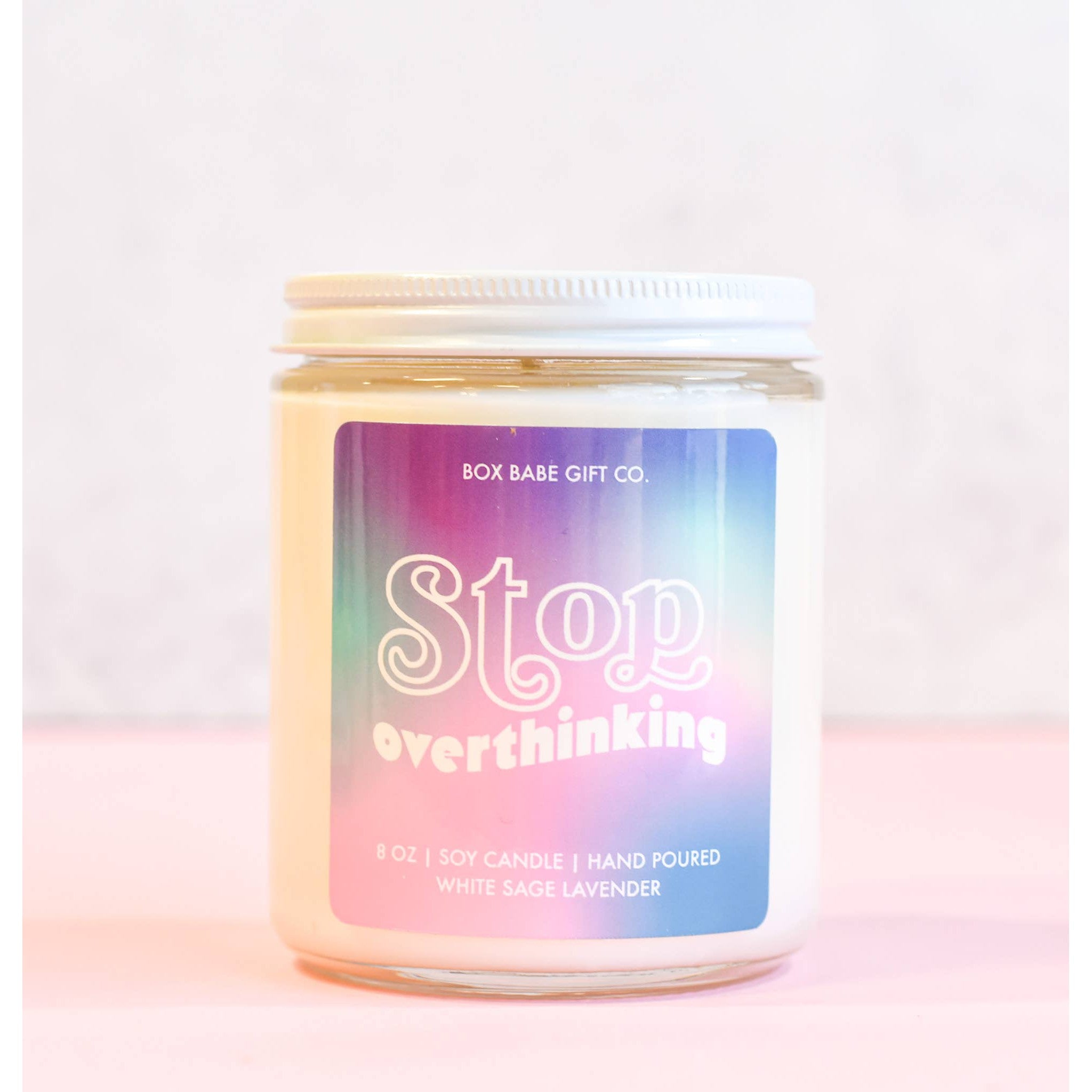 Candle jar with a colorful label on a light pink background