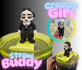 Straw buddy with a creepy girl figurine on top, held by a hand.