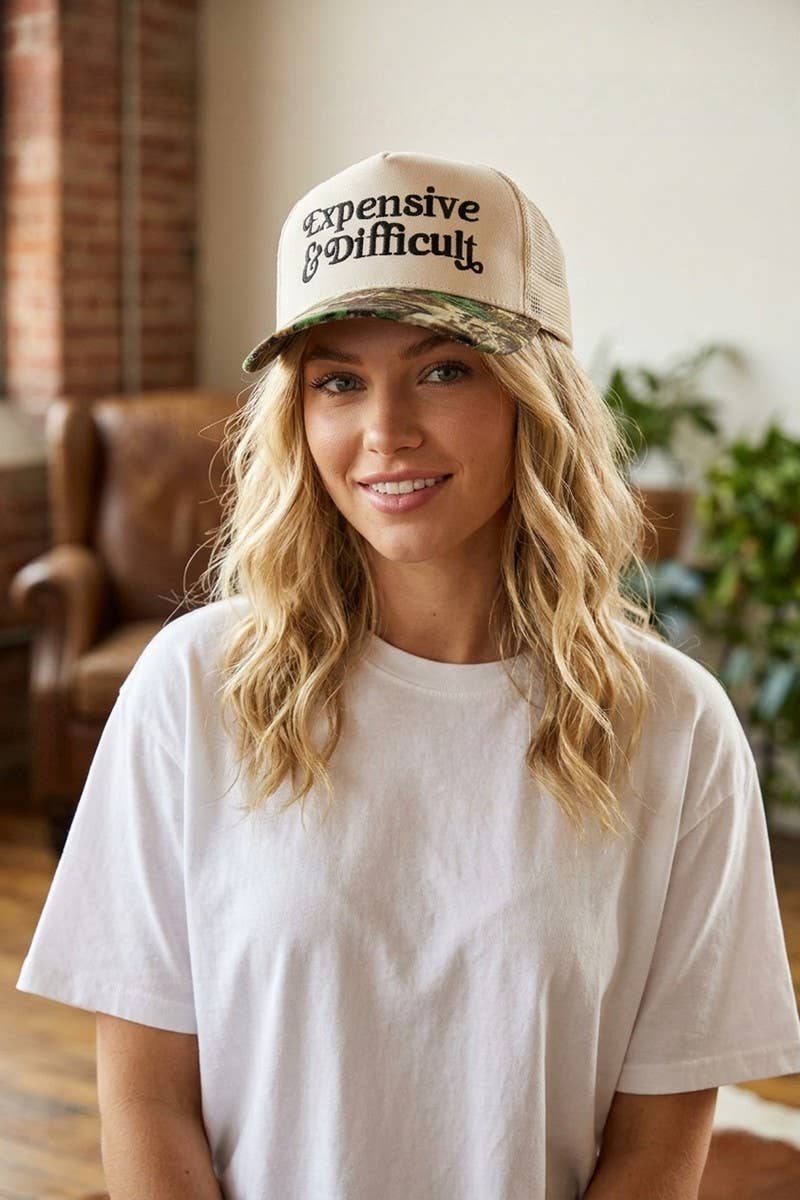 Woman wearing a cap with 'Expensive & Difficult' text in an indoor setting